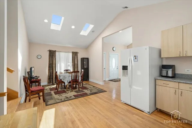 a living room with stainless steel appliances kitchen island granite countertop a refrigerator a stove and a dining table with wooden floor