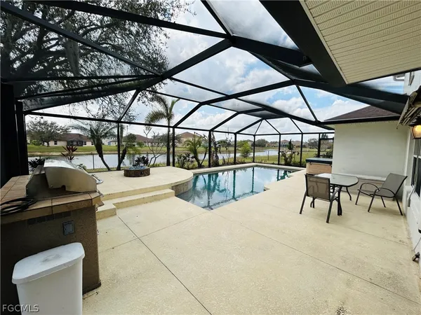 a view of a patio with a table and chairs under an umbrella with a small garden