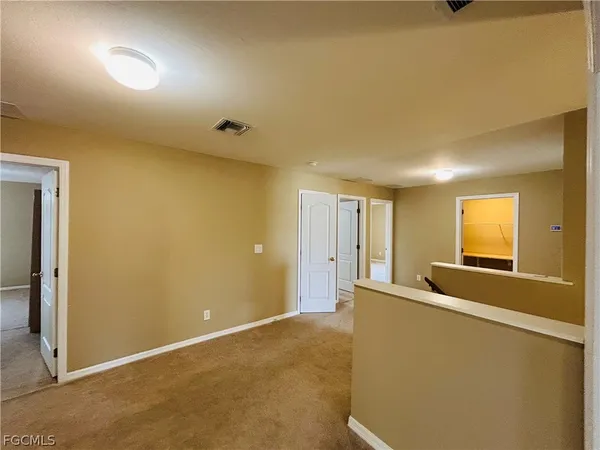 an empty room with chandelier fan and windows