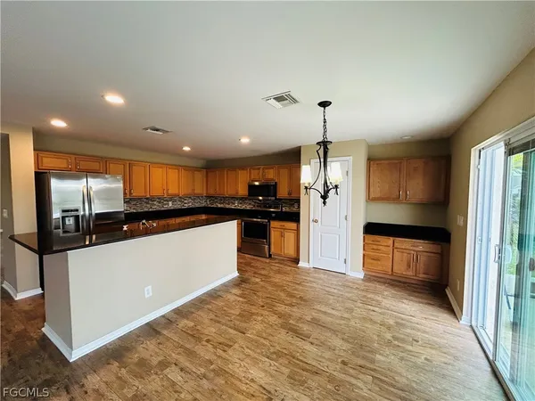 a large kitchen with stainless steel appliances a large counter top a stove and a refrigerator