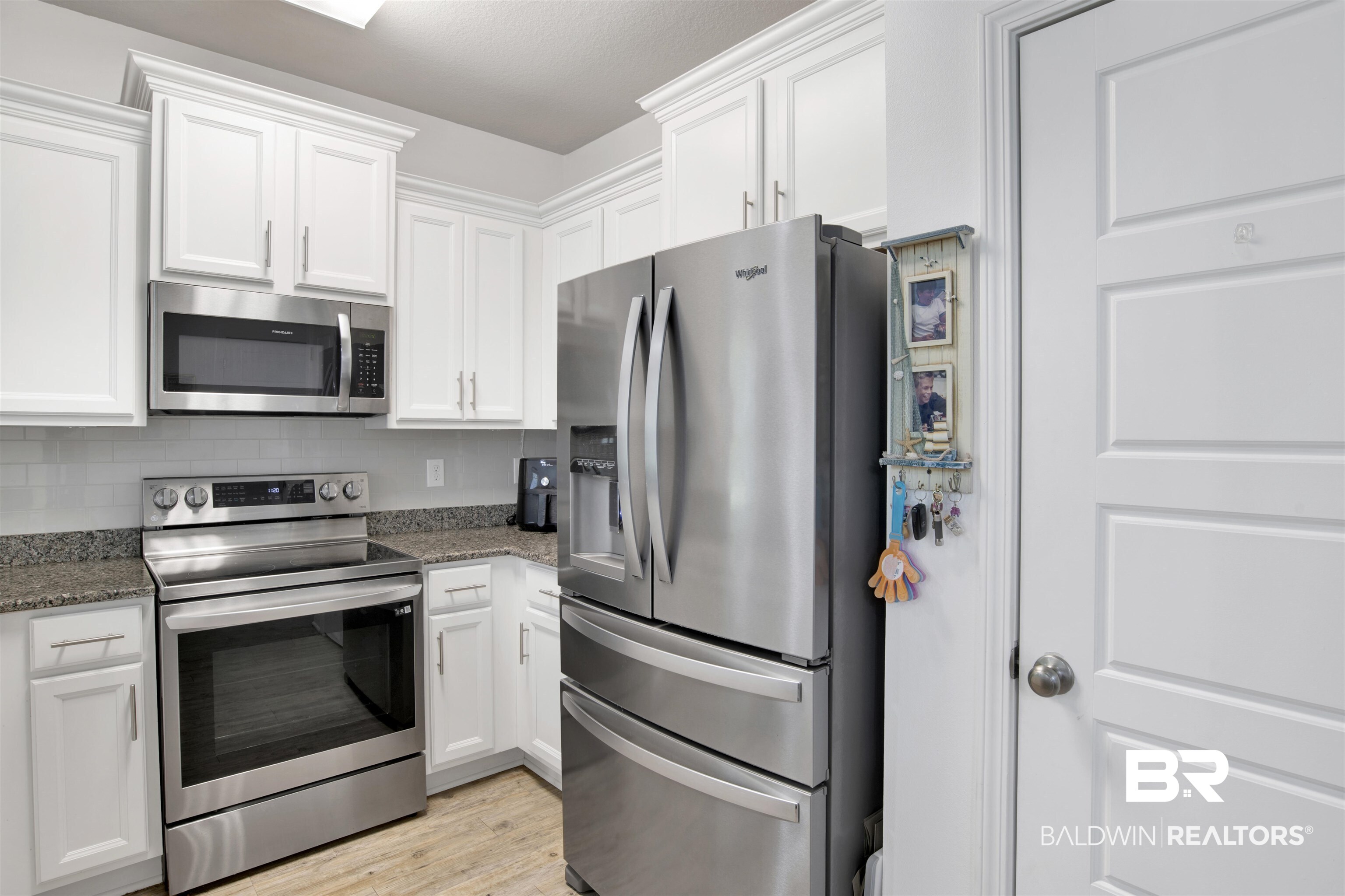 25806 Pollard Road, Unit 20 Daphne, AL 36526 - Photo 7 of 29 Kitchen with appliances with stainless steel finishes, white cabinetry, light stone counters, and light wood-type flooring