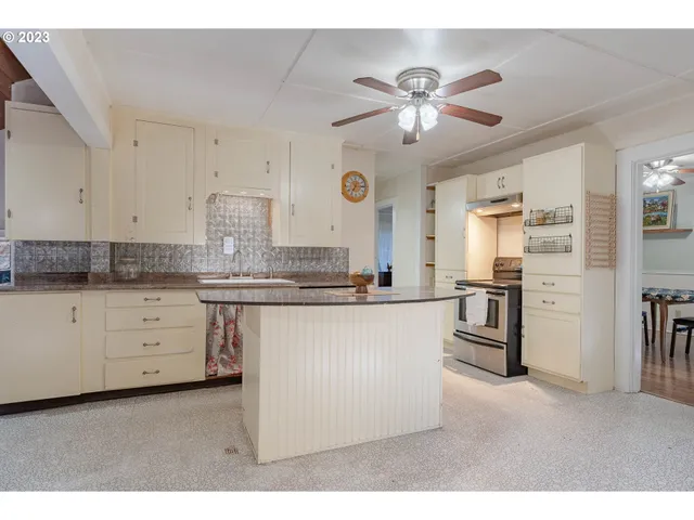 a kitchen with granite countertop a refrigerator a sink and white cabinets
