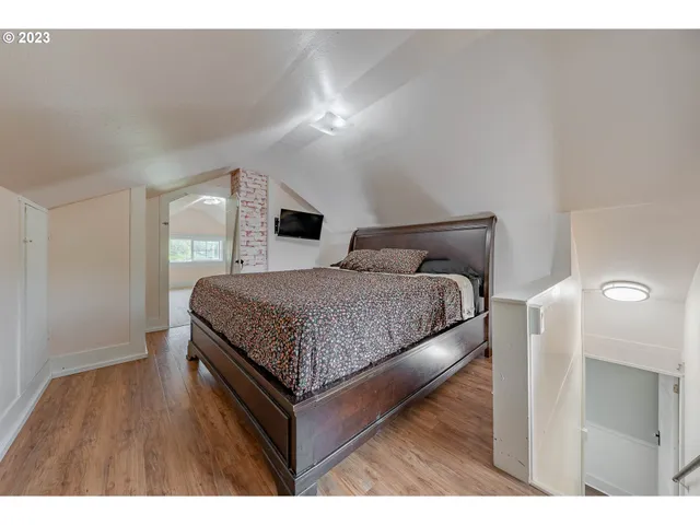 a bedroom with a bed and a night stand with wooden floor