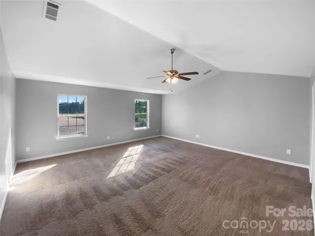 an empty room with windows and chandelier fan