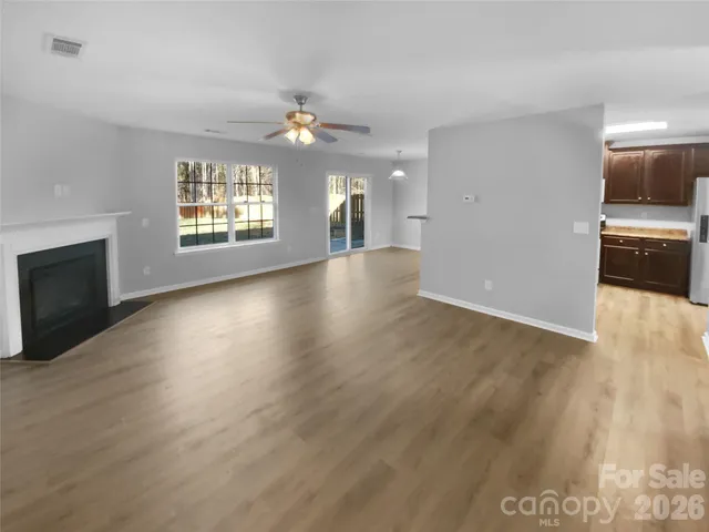 an empty room with wooden floor fireplace and windows
