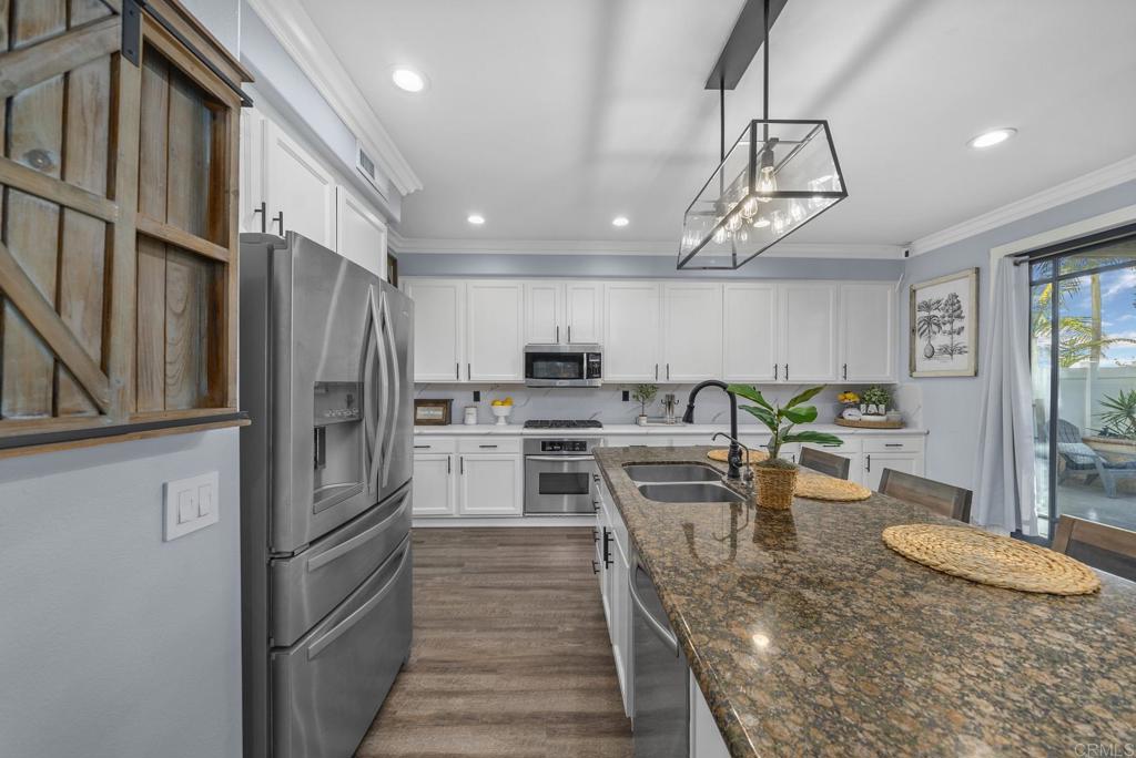 23 Wayfaire Rancho Santa Margarita, CA 92688 - Photo 15 of 44 a kitchen with stainless steel appliances granite countertop a refrigerator a sink dishwasher a stove and a dining table with wooden floor