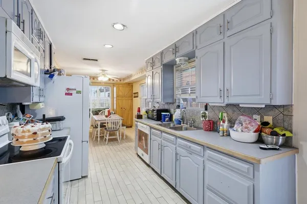 a kitchen with stainless steel appliances kitchen island granite countertop a refrigerator a sink dishwasher and white cabinets with wooden floor