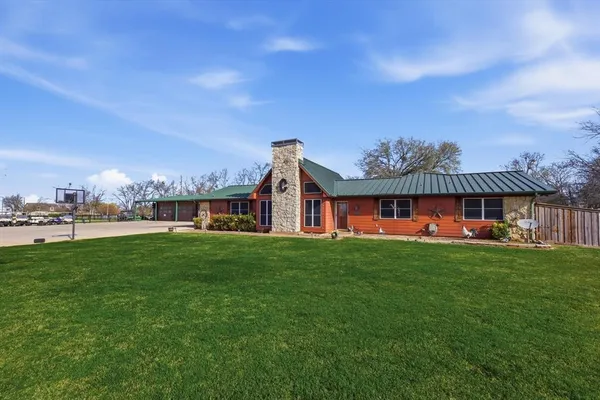 a view of a big house with a big yard plants and large trees