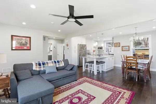 a living room with furniture kitchen view and a wooden floor