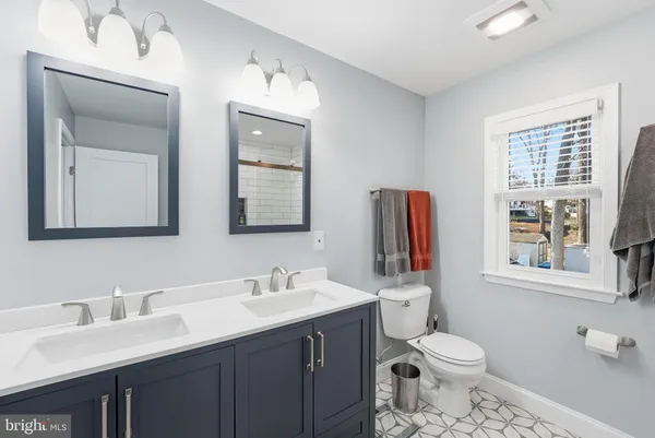 a bathroom with a toilet sink double vanity and mirror