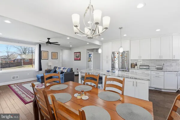 a very nice looking dining room with kitchen island furniture a chandelier and kitchen view