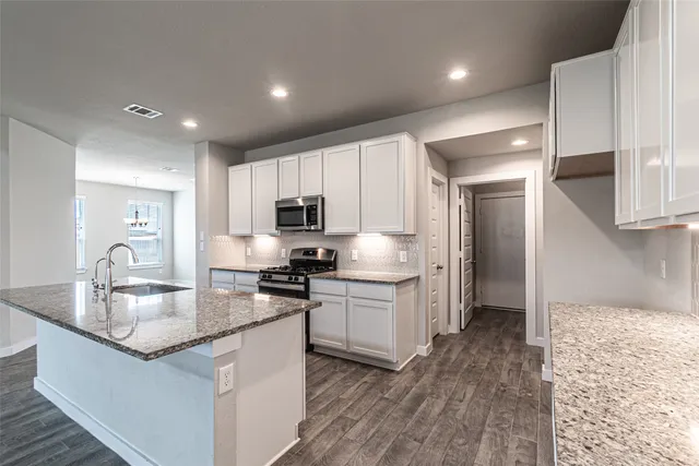 a kitchen with stainless steel appliances granite countertop a sink stove refrigerator and cabinets