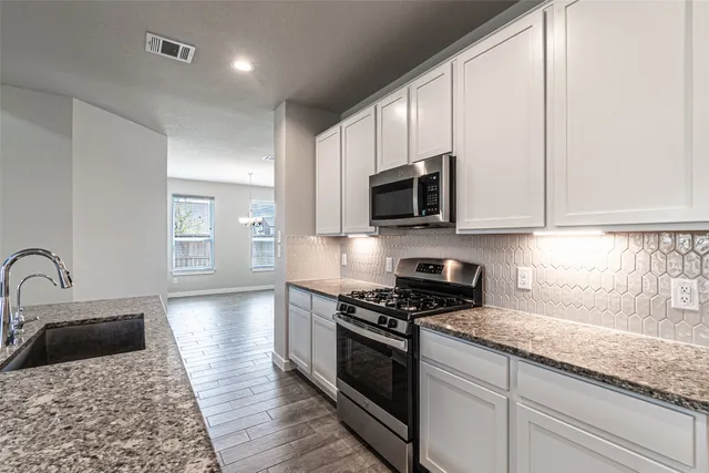 a kitchen with stainless steel appliances granite countertop a stove a sink and a microwave