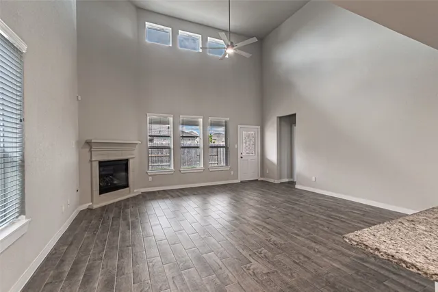 an empty room with wooden floor fireplace and windows