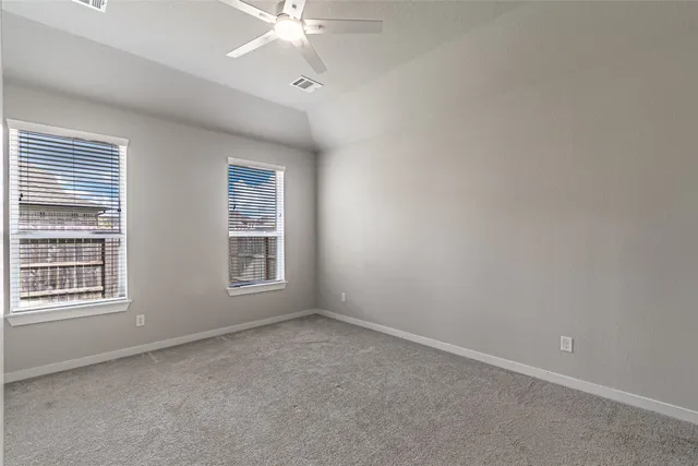 an empty room with windows and fan