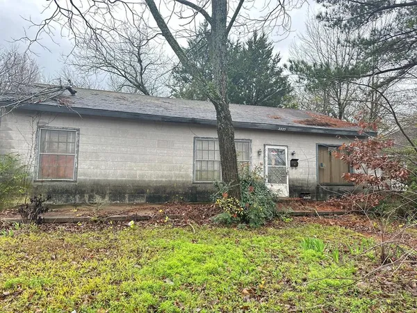 a backyard of a house with large trees and brick wall