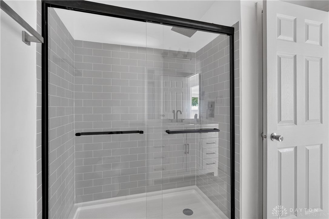 1243 Student Avenue Springfield, OH 45503 - Photo 19 of 38 Crisp subway tile lines the modern walk-in shower with sleek glass doors.