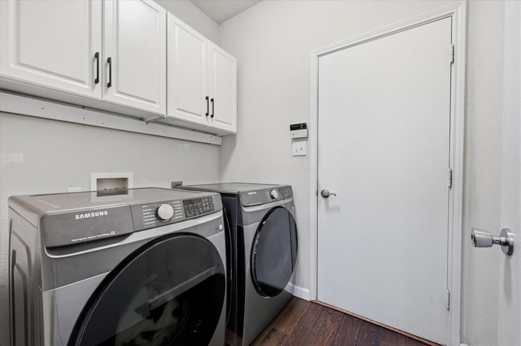 3413 Westfork Ranch Road Fort Worth, TX 76262 - Photo 25 of 35 Dedicated laundry area featuring white upper cabinetry with black hardware, rich wood-finish flooring, and light gray wall paint