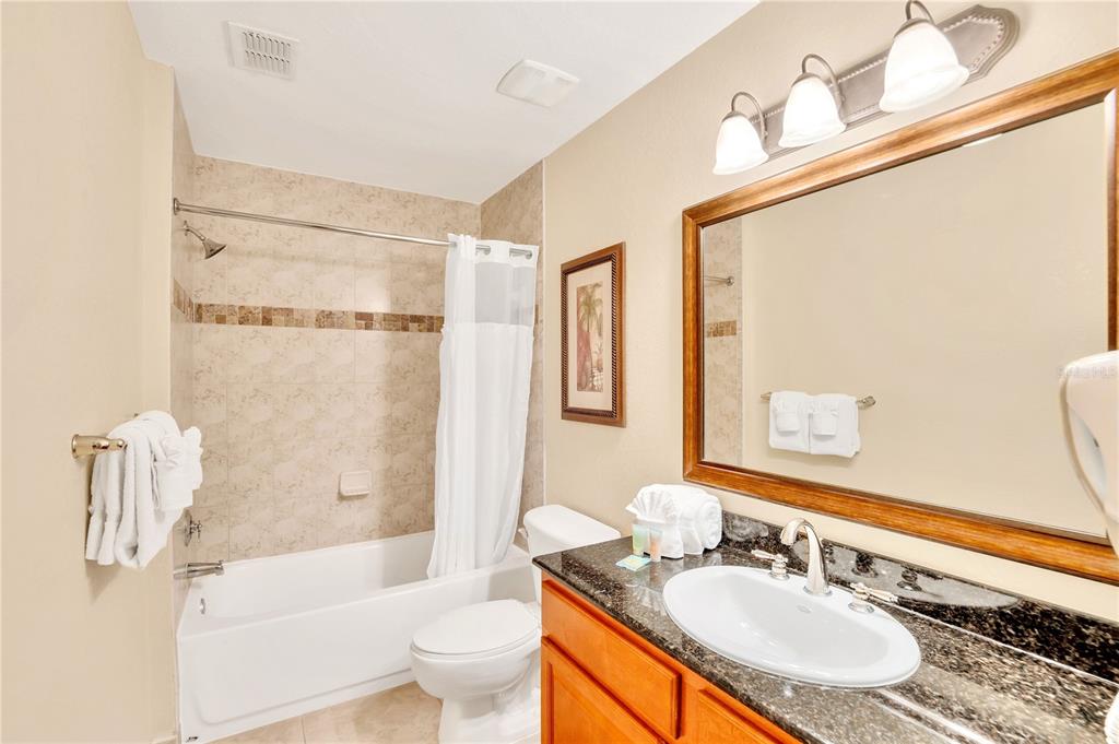 8113 Resort Village Drive, Unit 4405 Orlando, FL 32821 - Photo 19 of 25 a bathroom with a sink a toilet a mirror a bathtub and shower
