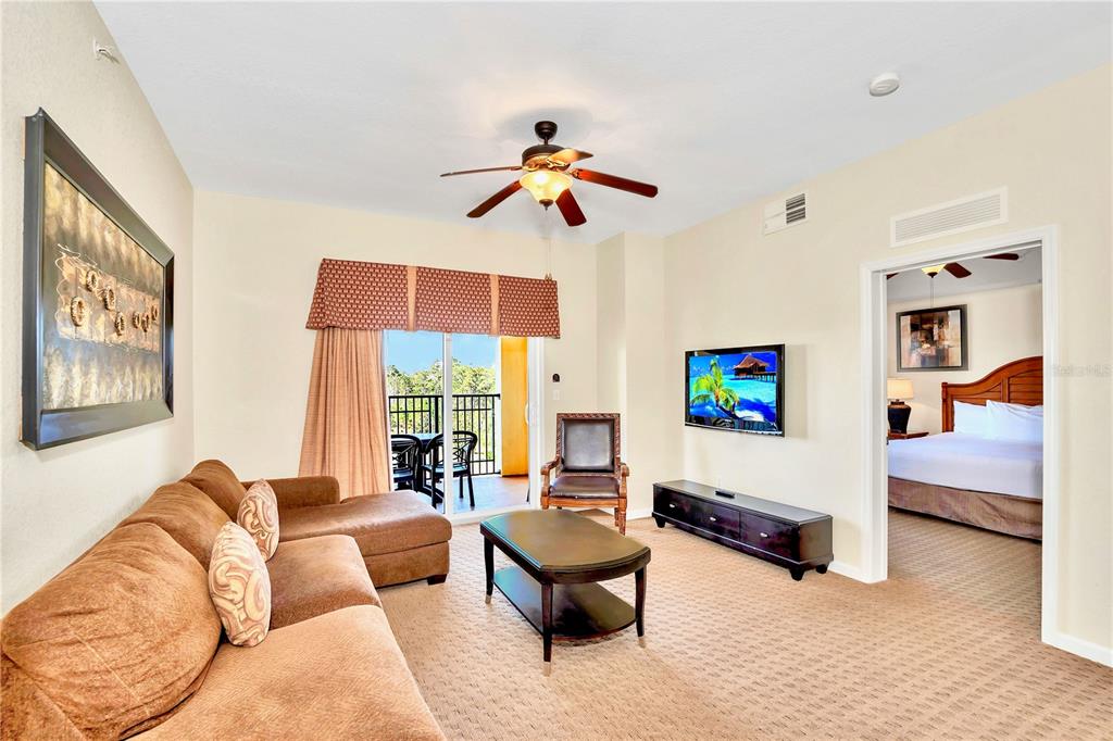 8113 Resort Village Drive, Unit 4405 Orlando, FL 32821 - Photo 3 of 25 a living room with furniture and a flat screen tv