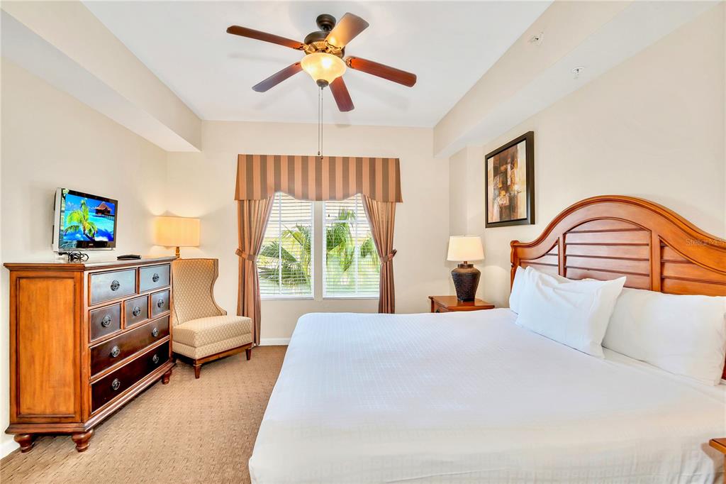 8113 Resort Village Drive, Unit 4405 Orlando, FL 32821 - Photo 5 of 25 a bedroom with a bed a couch and a chandelier