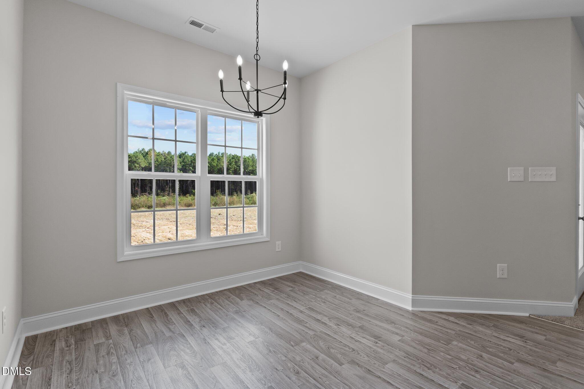 506 Bill Avery Road Coats, NC 27521 - Photo 5 of 21 an empty room with wooden floor chandelier and windows