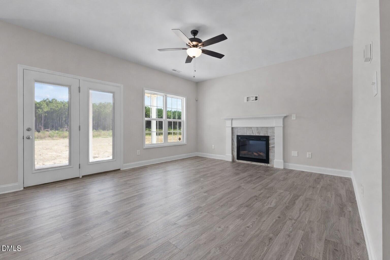 506 Bill Avery Road Coats, NC 27521 - Photo 7 of 21 an empty room with wooden floor fireplace and windows