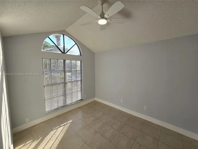an empty room with a chandelier fan and windows