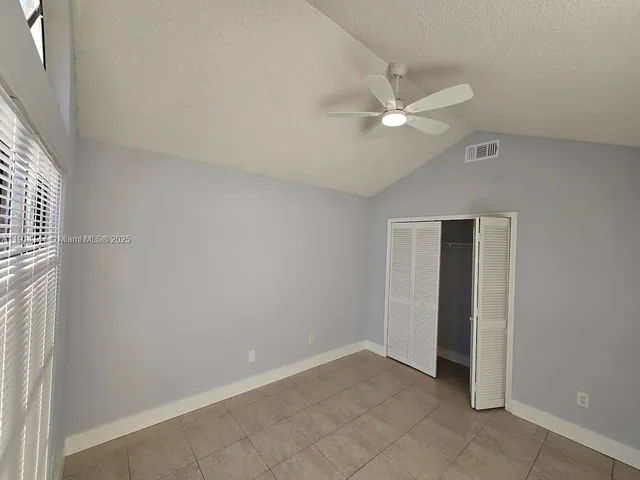 an empty room with closet and a chandelier fan
