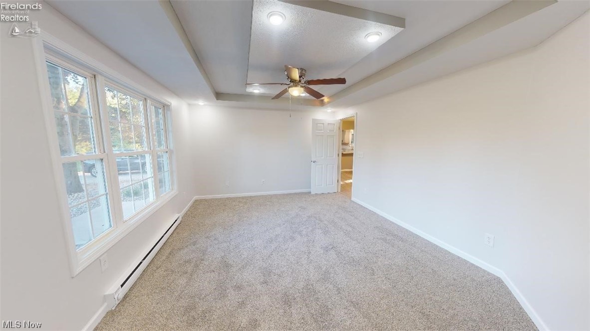 1715 Chenango Road Wakeman, OH 44889 - Photo 11 of 21 Carpeted spare room with baseboard heating, ceiling fan, and a tray ceiling