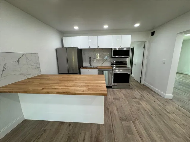 a large kitchen with stainless steel appliances granite countertop a stove and a refrigerator