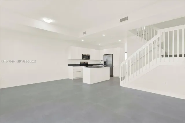 a view of kitchen with granite countertop cabinets and refrigerator
