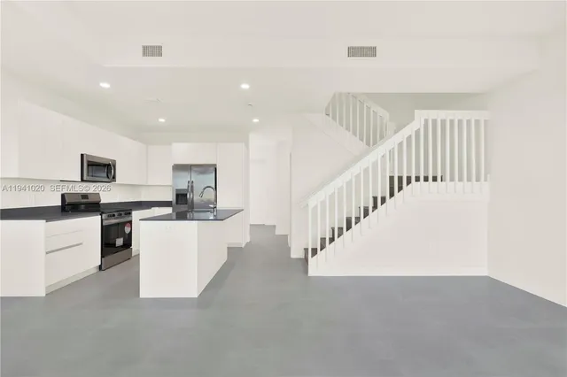 a kitchen with stainless steel appliances granite countertop a sink and a stove top oven with wooden floor