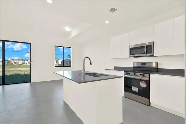 a kitchen with stainless steel appliances granite countertop a stove a microwave and a sink