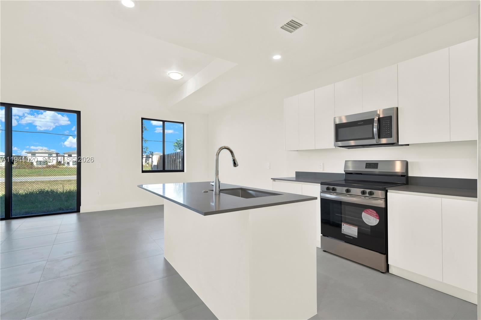 18981 Southwest 344th Terrace, Unit 18981 Homestead, FL 33034 - Photo 4 of 34 a kitchen with stainless steel appliances granite countertop a sink and a stove top oven with wooden floor