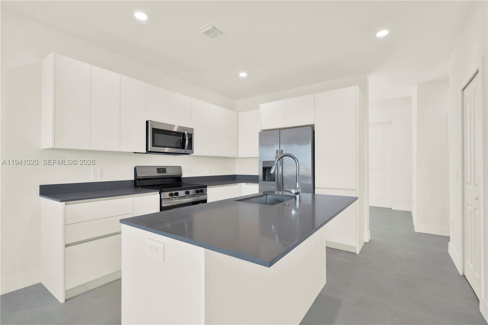 18981 Southwest 344th Terrace, Unit 18981 Homestead, FL 33034 - Photo 7 of 34 a kitchen with stainless steel appliances granite countertop a sink refrigerator and microwave