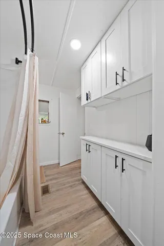 a view of a kitchen with white cabinets and wooden floor
