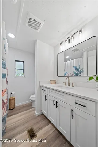 a spacious bathroom with a toilet a double vanity sink and a mirror