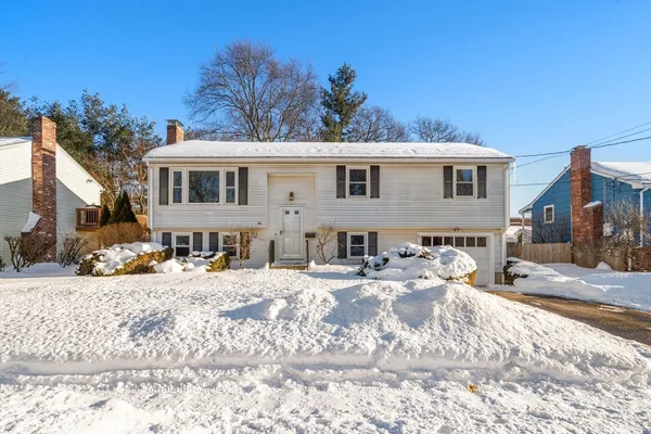 a front view of a house with a yard covered with snow