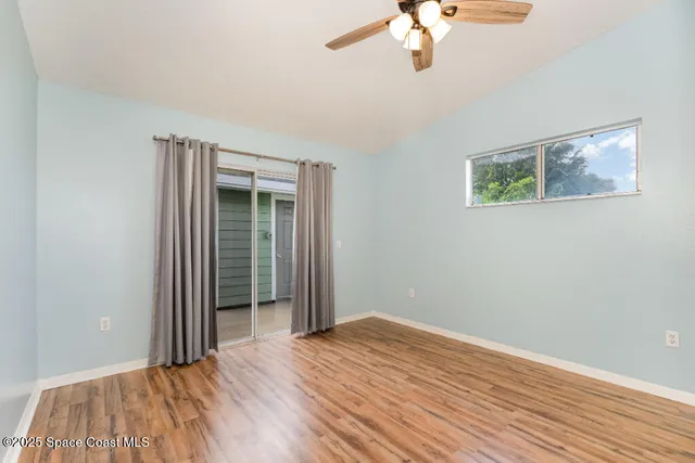 a view of a bedroom with wooden floor and a ceiling fan