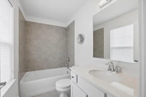 a bathroom with a bathtub shower sink vanity mirror and toilet