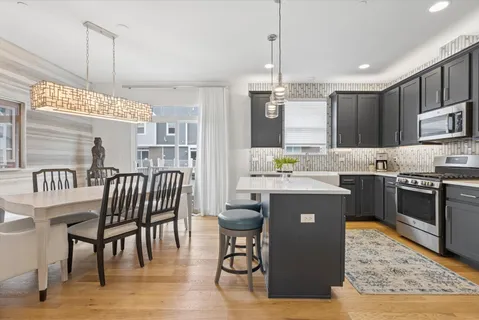 a kitchen with kitchen island granite countertop a stove a sink a dining table and chairs with wooden floor