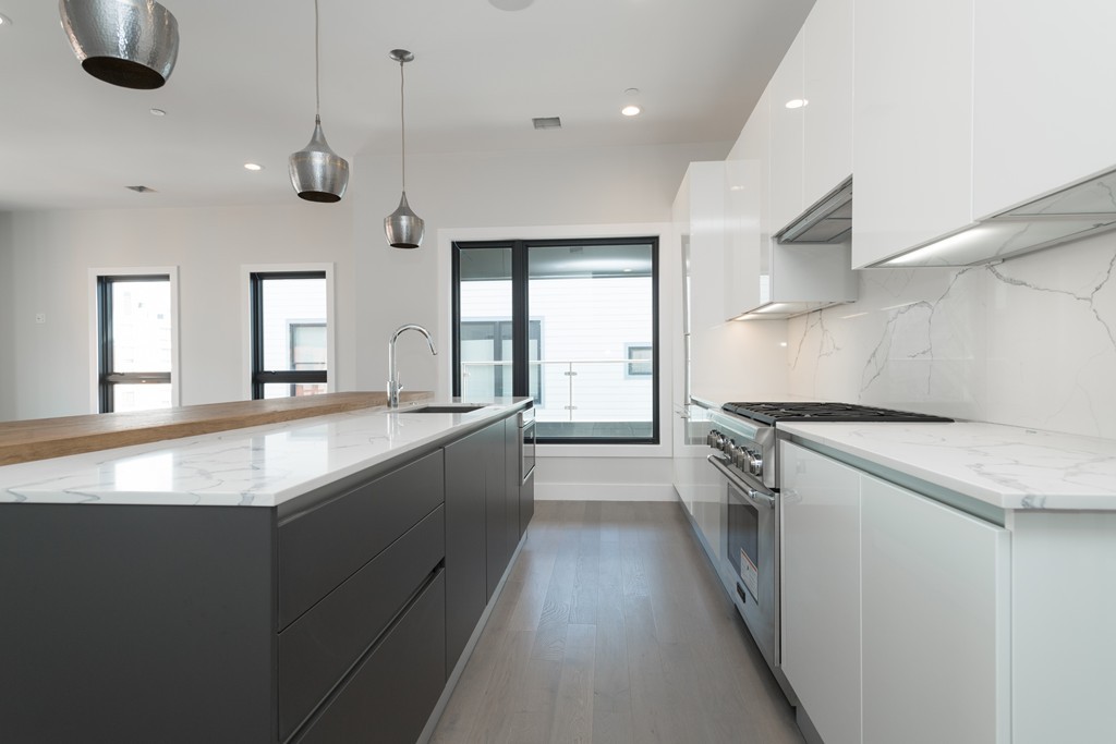 51 Silver Street, Unit 8 Boston, MA 02127 - Photo 1 of 10 a large kitchen with kitchen island a stove a sink dishwasher and a refrigerator with wooden floor