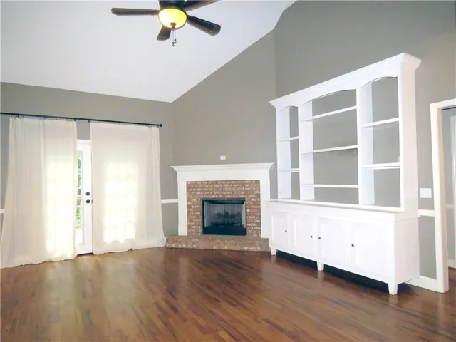 a view of an empty room with window and wooden floor