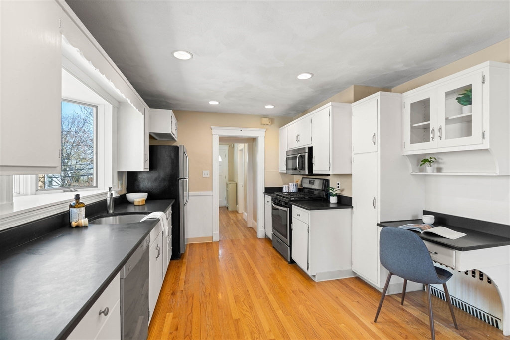 156 Russett Road Boston, MA 02132 - Photo 13 of 32 a kitchen with stainless steel appliances a stove a sink dishwasher a refrigerator white cabinets and wooden floor