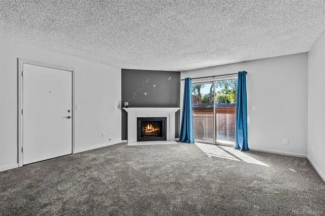 a view of an empty room with a window and fireplace