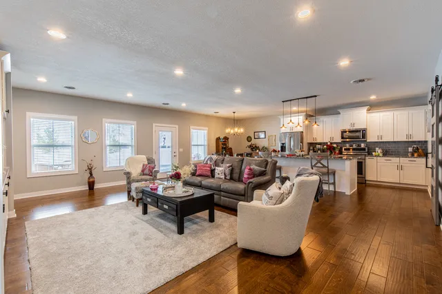 a living room with furniture and kitchen view with wooden floor