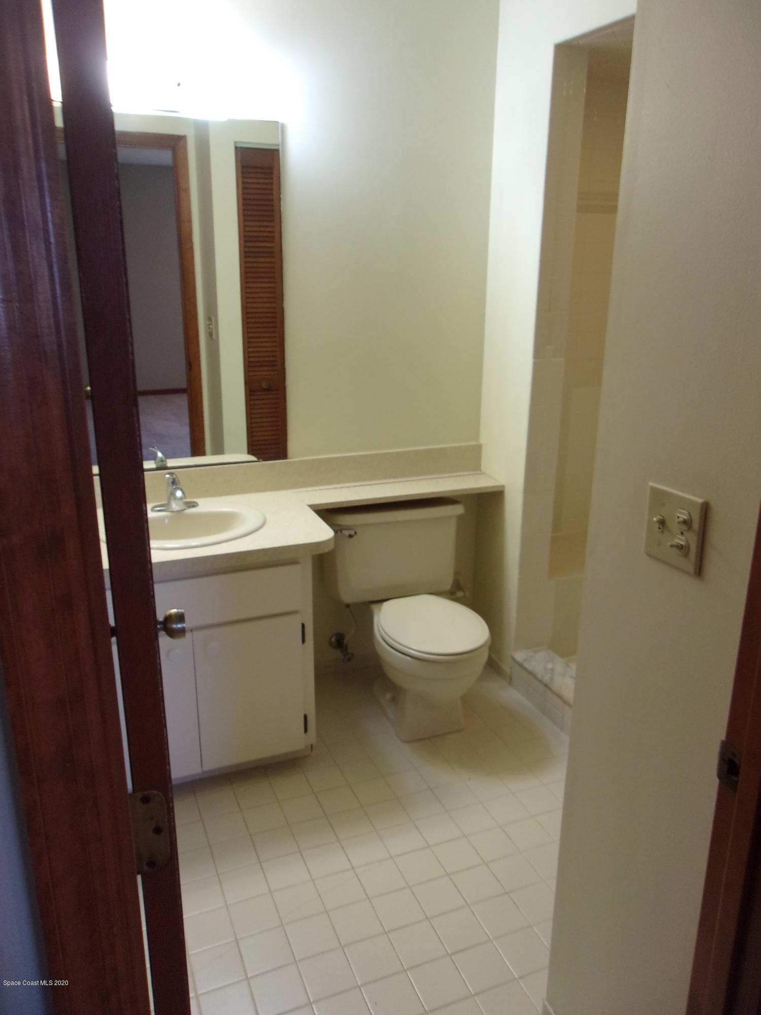 418 South Atlantic Avenue, Unit 3 Cocoa Beach, FL 32931 - Photo 19 of 29 a bathroom with a toilet sink and mirror