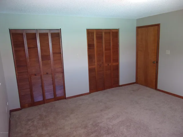 an empty room with closet and mirror