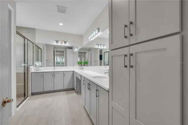 a large white kitchen with a large vanity a sink stainless steel appliances and cabinets